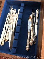 Flatware knives and some forks neatly arranged inside a blue velvet casket with compartments