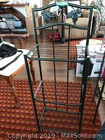 Mini metal bakers rack with decorative top and black metal frame on carpeted floor