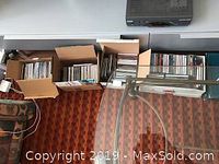 Photo showing boxes and albums of music CDs arranged on floor beneath a glass table.