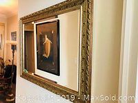 Wide angled photo showing the full rectangular mirror hanging on a wall next to framed artwork, illustrating its size and shape.