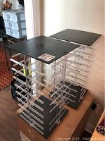 Photo showing two plastic jewellery stands with black bases and tops, and clear horizontal rods for displaying jewelry.