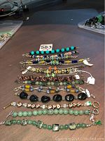 Photo showing multiple bracelets with colorful beads and metal chain links arranged in a row on a flat surface.