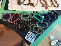 Photo showing 15 costume jewellery bracelets arrayed on a black surface, various bead colors and styles visible.