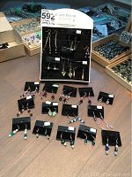 Overview of 20 pairs of costume jewelry earrings arranged on a table with a black foam jewelry stand holding some of them.