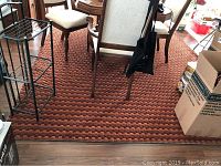 Area rug under dining table with chairs and other household items around it. Shows textured orange and brown circular pattern.