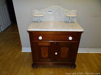 Front view of the vintage washstand showing marble top, drawer and double doors with white knobs.