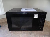 Front view of black Panasonic microwave with manual on top