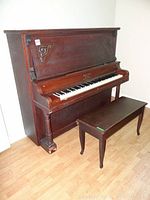 Full view of upright Willis & Co. piano showing dark wood finish, carved accents, and matching bench.