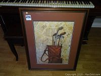 Full view of framed golf clubs print set on the floor with piano in background