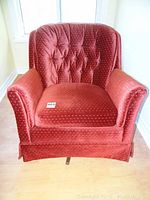 Front view of rust-colored upholstered swivel rocker tub chair showing cushioned seat, rolled arms and skirted base.