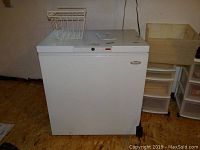 Front view of the white Woods chest freezer with the lid closed and wire basket on top, showing dimensions and clean condition.