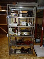 Front-facing view of the 5 tier metal storage shelf loaded with assorted kitchenware and decorative items.