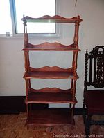 Front view of the five-tier solid wood shelf with carved scalloped edges and turned supports, showing wood finish and style.