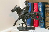 Front left angle showing full statue on base with books in background
