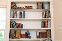 Full view of built-in bookshelf with multiple shelves displaying leather bound Franklin Library books, miniature Shakespeare series, and other hardcovers.