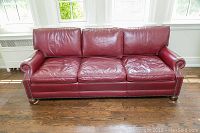 Front view of full couch showing seat cushions, rolled arms, nailhead trim and bun feet