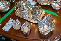 Overview of tray holding lidded sugar bowl and creamer with three pierced nut baskets
