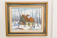 Full view of the framed oil painting showing the winter cabin scene with snow and trees.