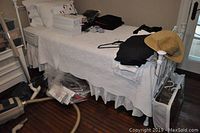 Photo showing single white cast metal bed frame with vertical bars and finials. Bedding is present but not included.