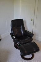 Front view of black leather chair and ottoman on wood bases