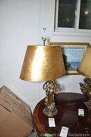 Front view of metal lamp on wooden table with painting in background