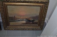 Front view of painting leaning against wall showing seascape scene and carved gold frame