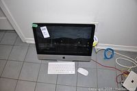 Front view of Apple iMac all-in-one computer with aluminum stand, black display bezel, seller label attached