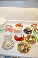 Overview of nine teacup and saucer sets on white table