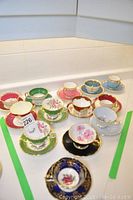View of six assorted bone china teacup and saucer pairs in various colors and floral gilt designs