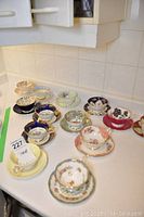 Overview of ten teacup and saucer sets on countertop
