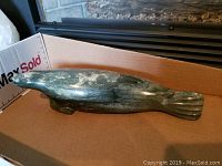 Side view of the greenish stone seal carving with visible natural stone wear and polished surface.
