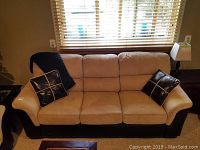 Front view of the three seater sofa showing beige suede cushions and black leather arms with two black pillows.