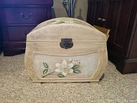Front view of a small wooden chest with hand-painted floral pattern and metal latch on front.