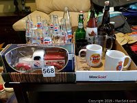 Overview photo showing the collection of glass Pepsi bottles, beer bottles, mugs, and the 1940 Ford die cast Pepsi bank still in the box.