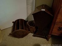 View of the antique double-lidded wooden storage box, hand-carved magazine holder, and ceramic vase with pine cones from the left angle