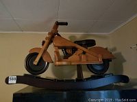 Side view of wooden motorcycle rocker showing pine construction and curved rocker base