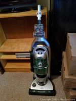 Upright Bissell vacuum cleaner with visible dust canister and base attachment.
