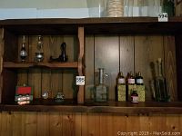 Overview of wooden shelves displaying a variety of glass bottles, metal and glass incense burners, metal cash register mini, meditation balls in a box, and a small decorative figure.