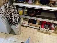 Tin pails with decorative twigs next to shelves holding candles and bowls
