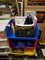 Full view of rolling shelving unit with three plastic bins containing coveralls, personal care items, and hair dryer