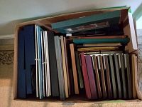 Top-down view of a box filled with assorted picture frames of different sizes and colors.