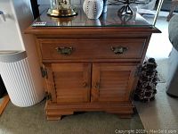 Front view of the wooden Vilas storage cabinet showing upper drawer with brass handles, two lower slatted doors, and protective glass top.