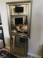 Full view of the large framed mirror showing a reflective surface with beveled edges and silver frame.