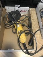 Photo of yellow Dewalt DW818 corded angle grinder with black cord, showing the whole tool and grinding disc.
