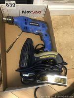 Blue Mastercraft corded drill with drill bit and Nail Master 2 electric nail gun in cardboard box.