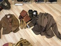Photo showing two brown leather jackets, boots, shoes, and jeans on a light wooden floor