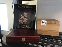 Photo of Roy Henry Vickers art book 'Copperman' alongside a dark polished wood box with clasp and a light unfinished wood box.