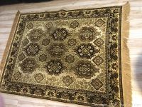 Full view of one beige and brown patterned throw rug with intricate floral and geometric motifs and fringe on two sides, laid on wooden floor.