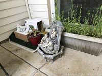 Wide angle photo showing the Smart Garden box, potted cactus, window box with live plants, and decorative fountain.