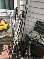 Fishing rods, ski poles, socket wrench set on bench, and part of a manual golf cart frame.